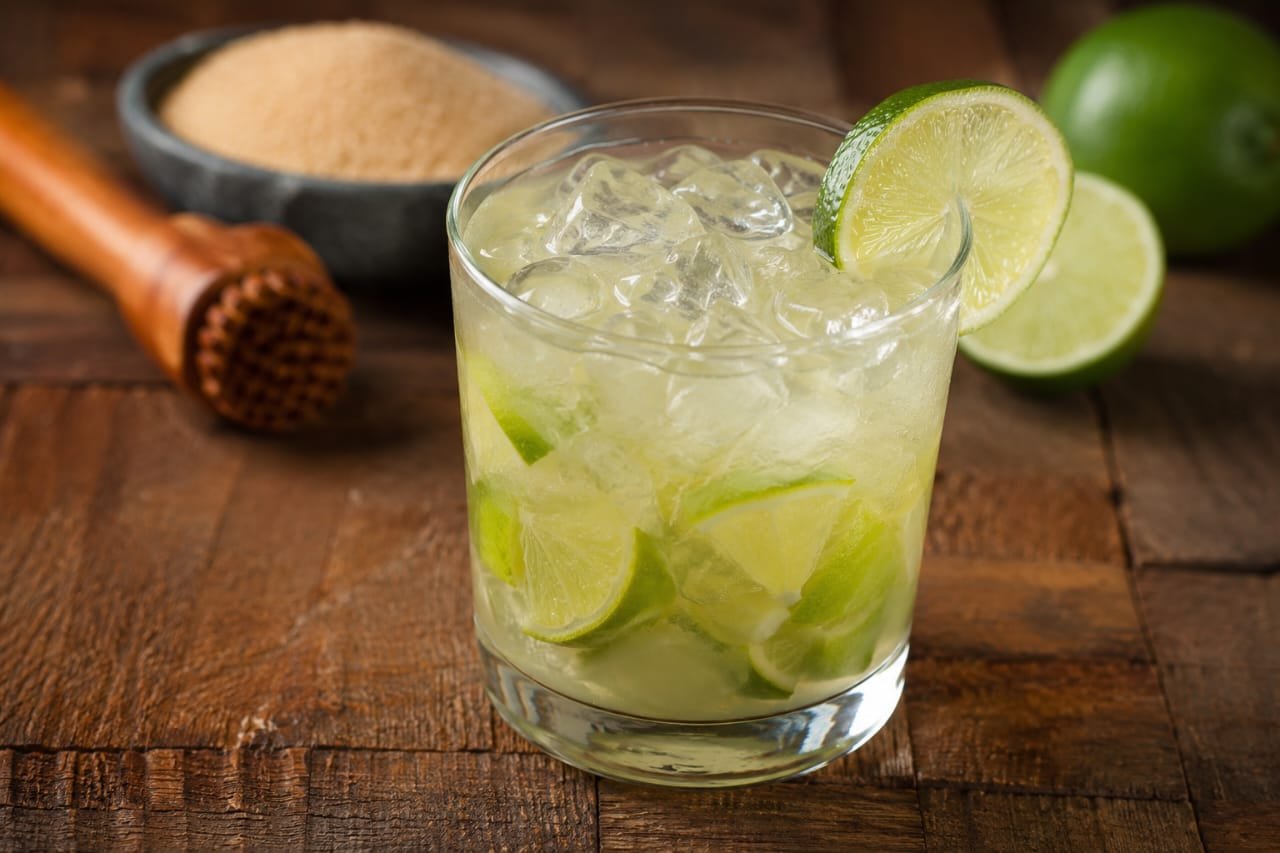 Coquetel Caipirinha tradicional brasileira com limão, gelo e cachaça servido em copo de vidro.